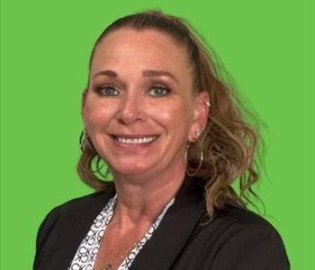 Woman in black blazer in front of green background.