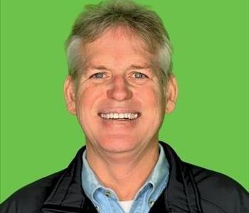 Man in polo shirt in front of green background.