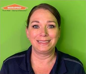 Woman in polo shirt in front of green background with orange logo in top left.