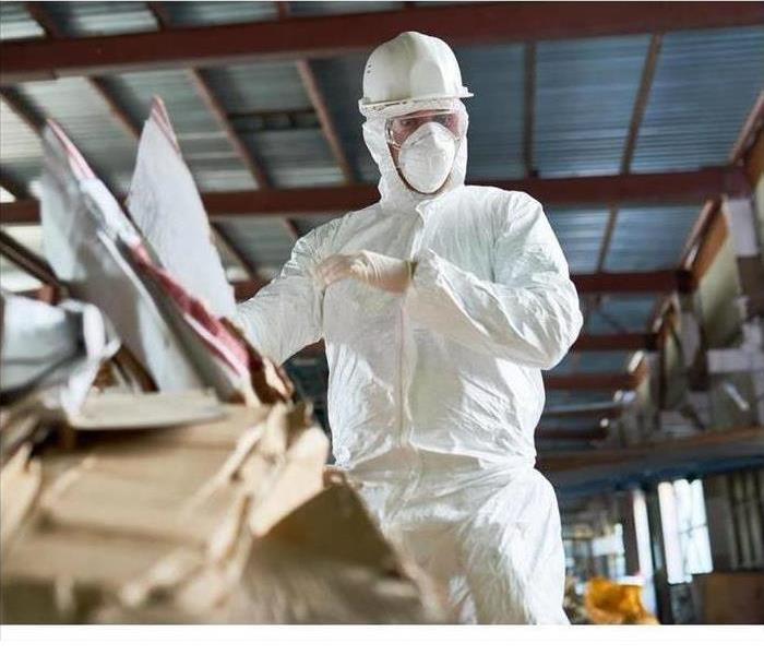 Worker in a biohazard suit cleaning up